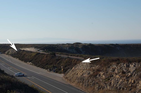 The inland view of the earthen berm on which the railroad tracks sit. The two arrows show the limits of the native bedrock, i.e., the Santa Cruz Mudstone. In between the arrows is all fill for the embankment.