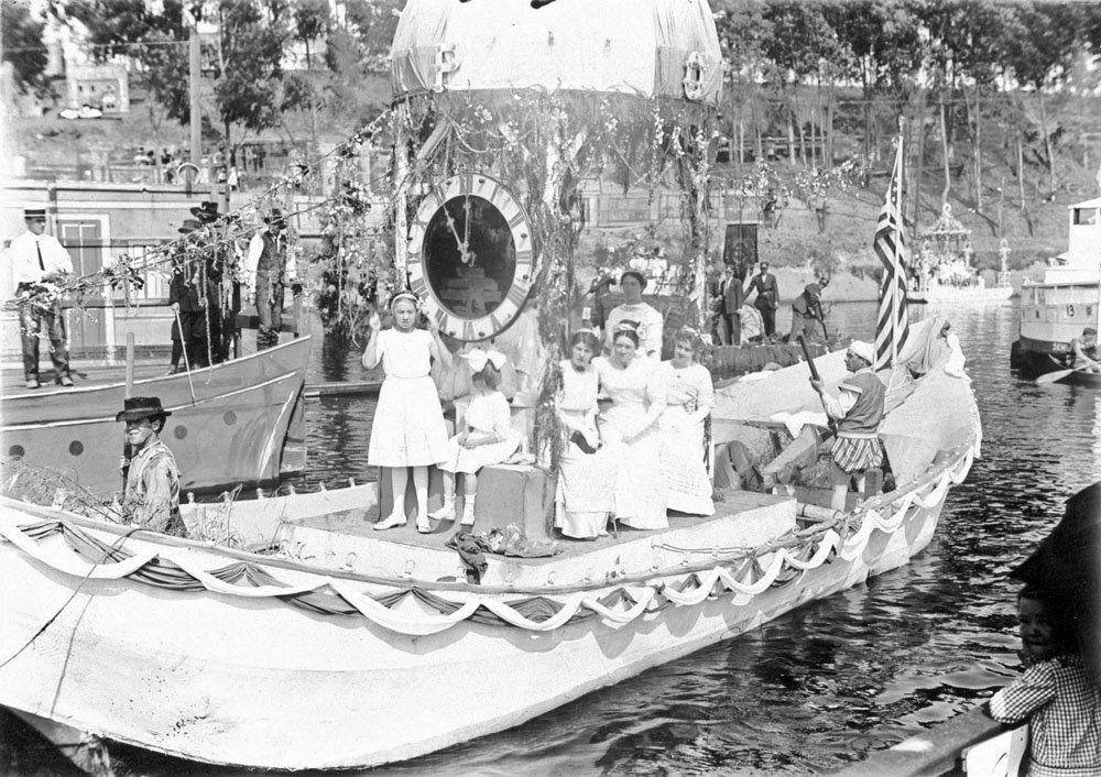 Girls dressed in white pose for a picture aboard a float during the Venetian Water Carnival on the San Lorenzo river. Picture courtesy of and copyright Santa Cruz Public Library.
