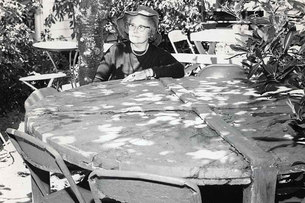 One of two picnic tables made from the original 1864 packing crate for the 3,800 pound cheese made by the Steele Family. Seated at table is Mrs. Catherine Steel. Photo circa 1950; courtesy of the Santa Cruz Museum of Art & History.